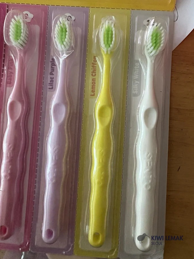 Four children's toothbrushes in packaging, part of a Korean daycare bag