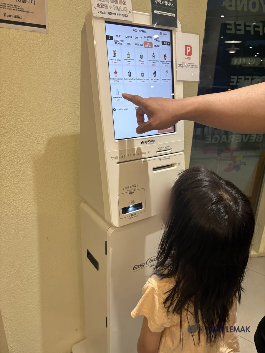 A child pointing at a self-order coffee kiosk screen