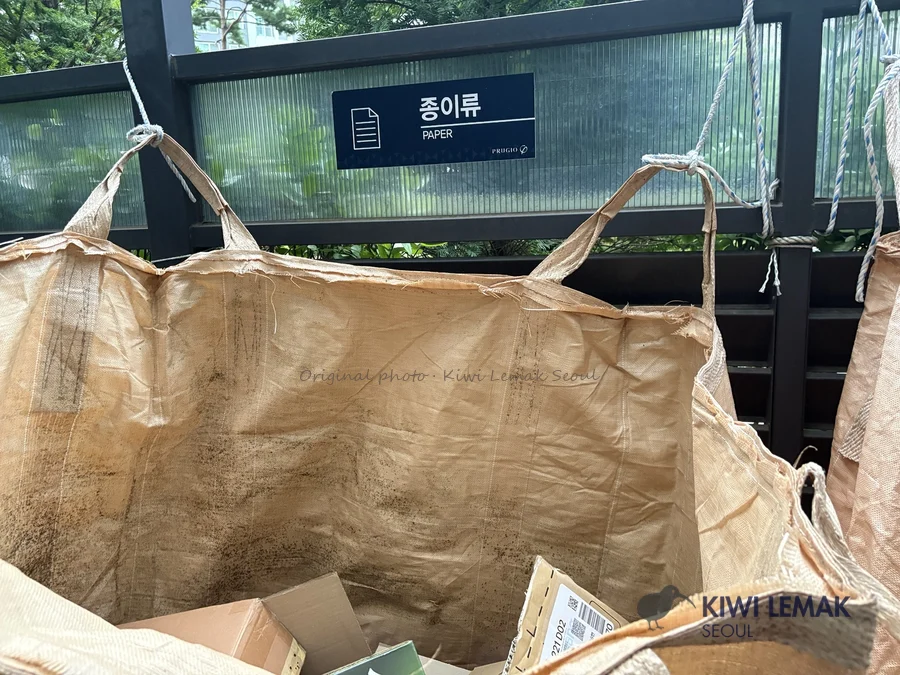 Paper recycling signage and bags in a Korean apartment complex recycling area